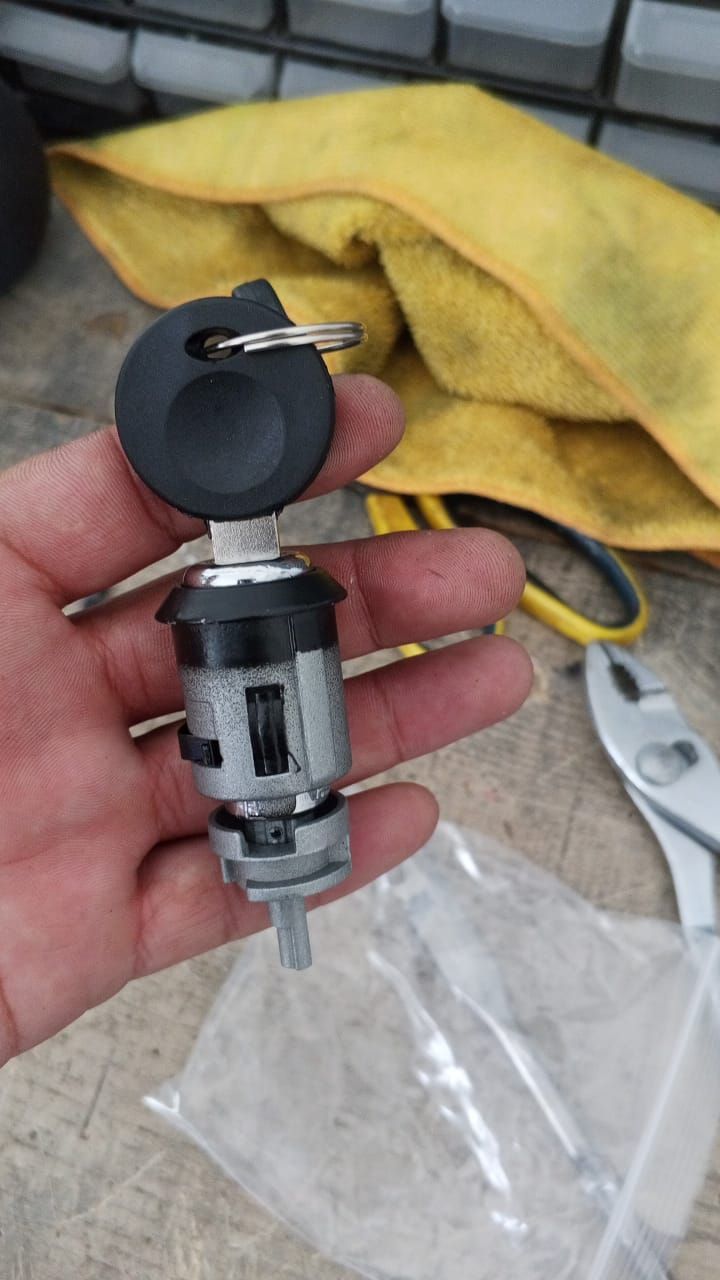 Mano sujetando el interruptor de encendido de un coche con la llave. El interruptor es plateado, negro y blanco.