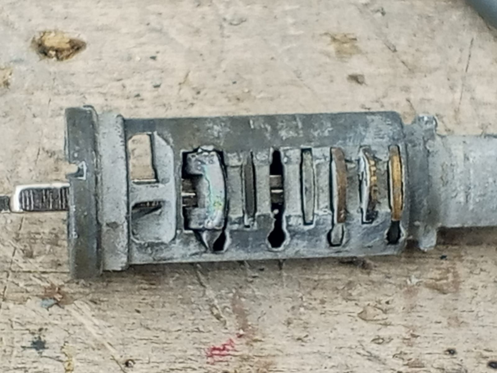 Cilindro de cerradura de encendido de automóvil dañado, metálico y parcialmente desmontado.