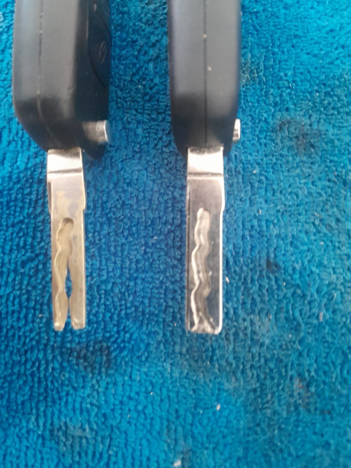 Dos llaves de coche una al lado de la otra; una con la llave limpia y la otra mostrando signos de desgaste.