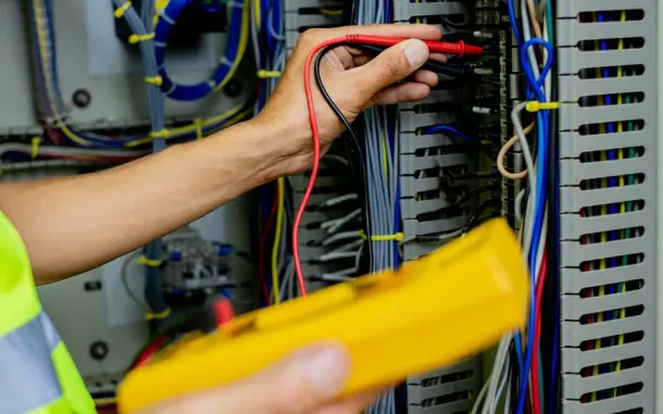 A person is using a multimeter to test a circuit board.