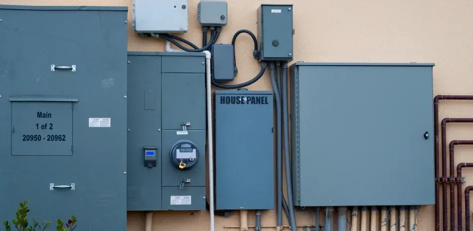 There are a lot of electrical boxes on the side of a building.