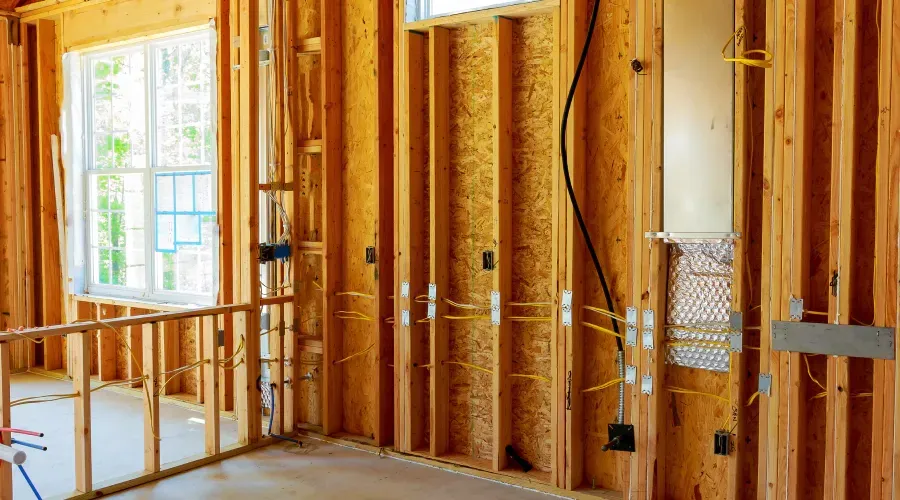 A room in a house under construction with wooden walls and a window.