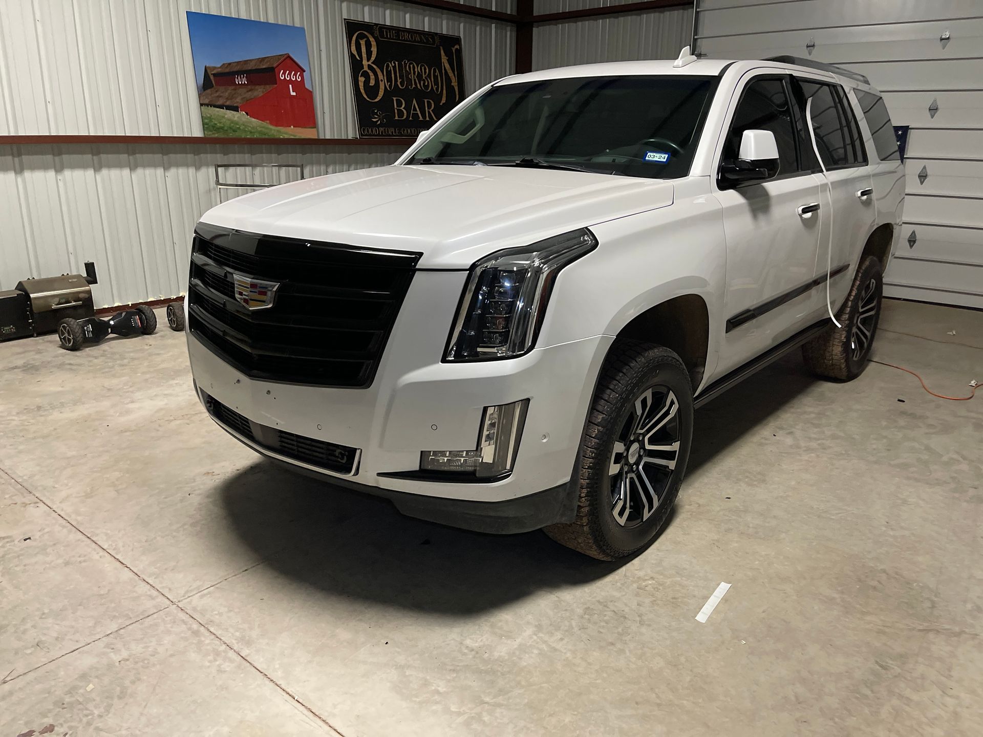 A white cadillac escalade is parked in a garage.