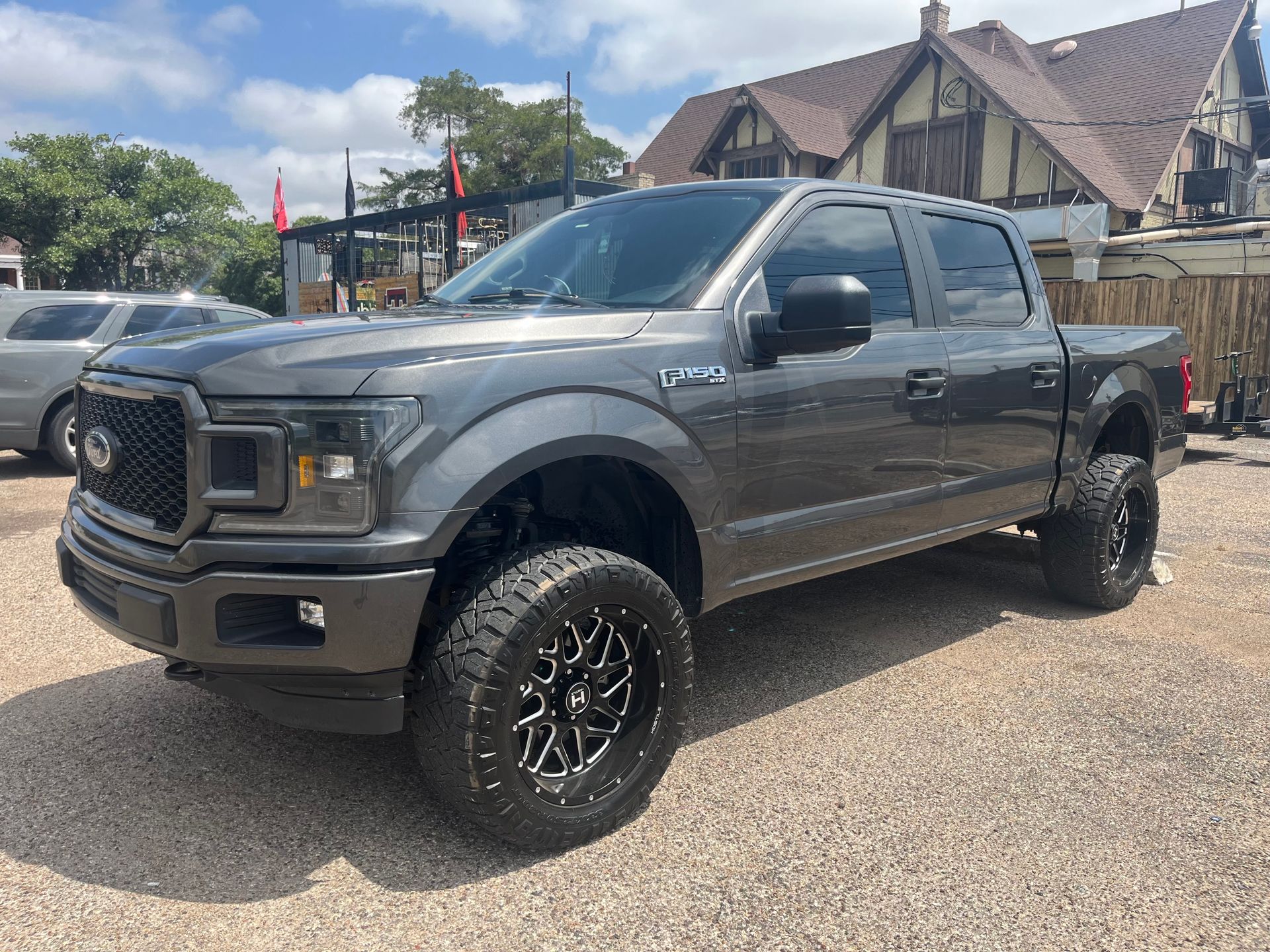 A gray ford f150 truck is parked in front of a house.
