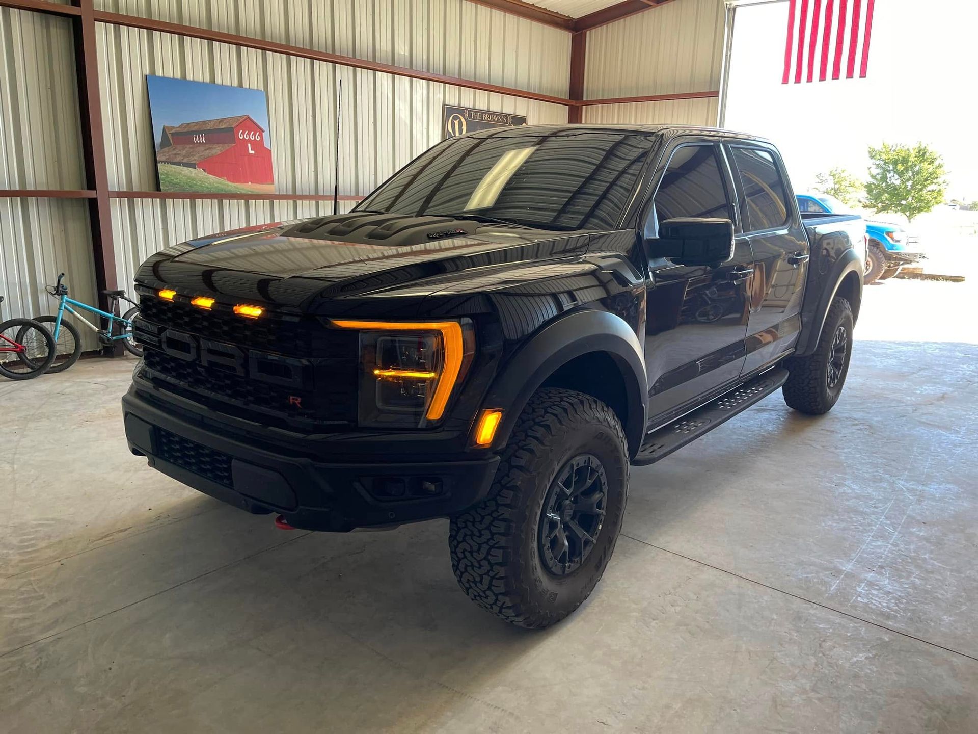 A black ford raptor is parked in a garage.