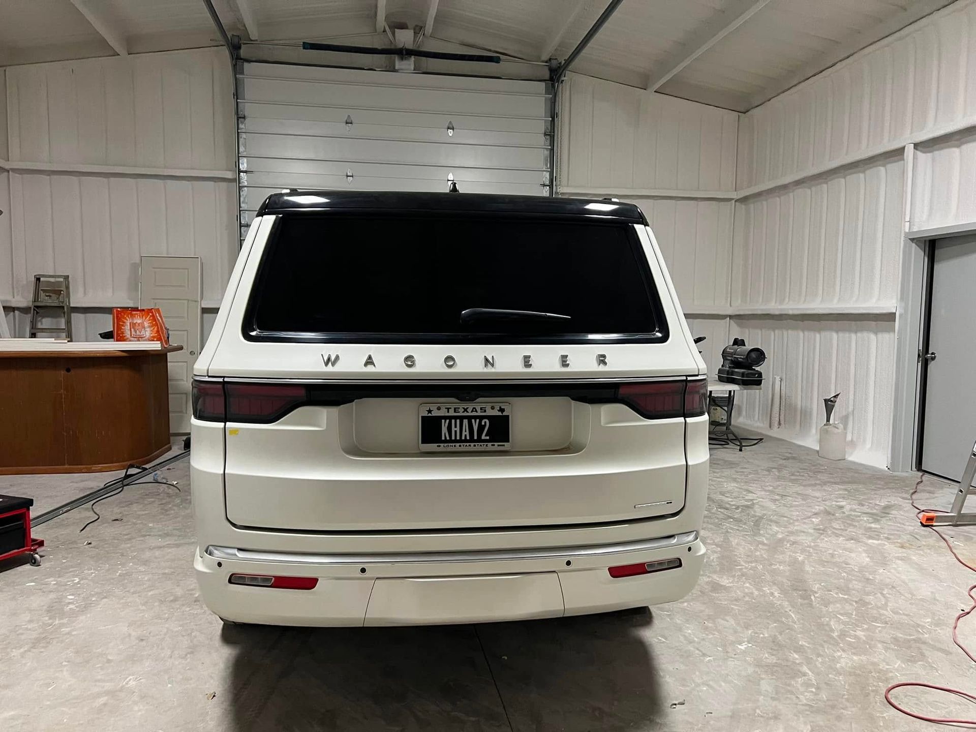 A white suv is parked in a garage with a garage door open.