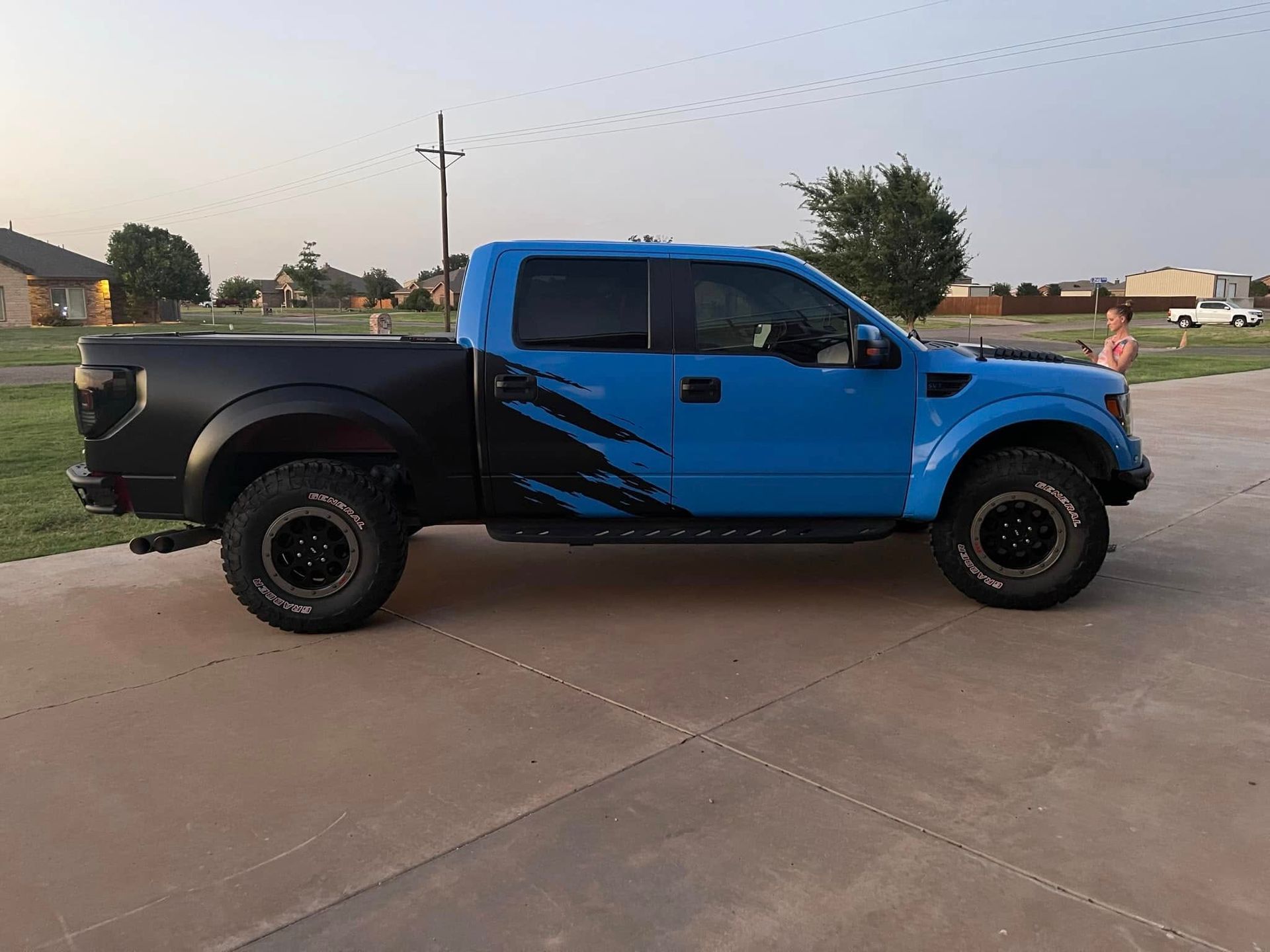 A blue and black truck is parked in a driveway.