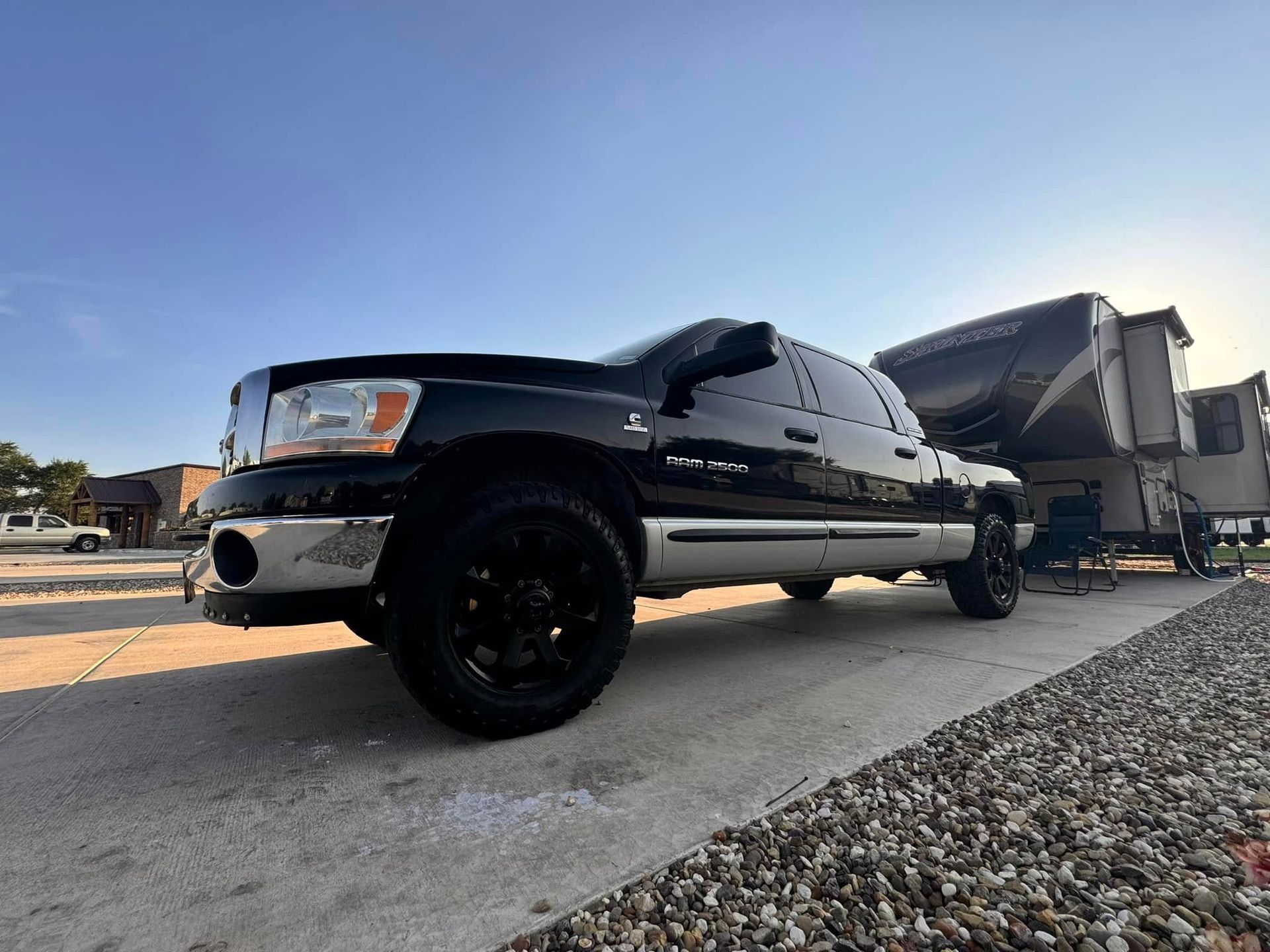 A black truck is parked on the side of the road next to a trailer.
