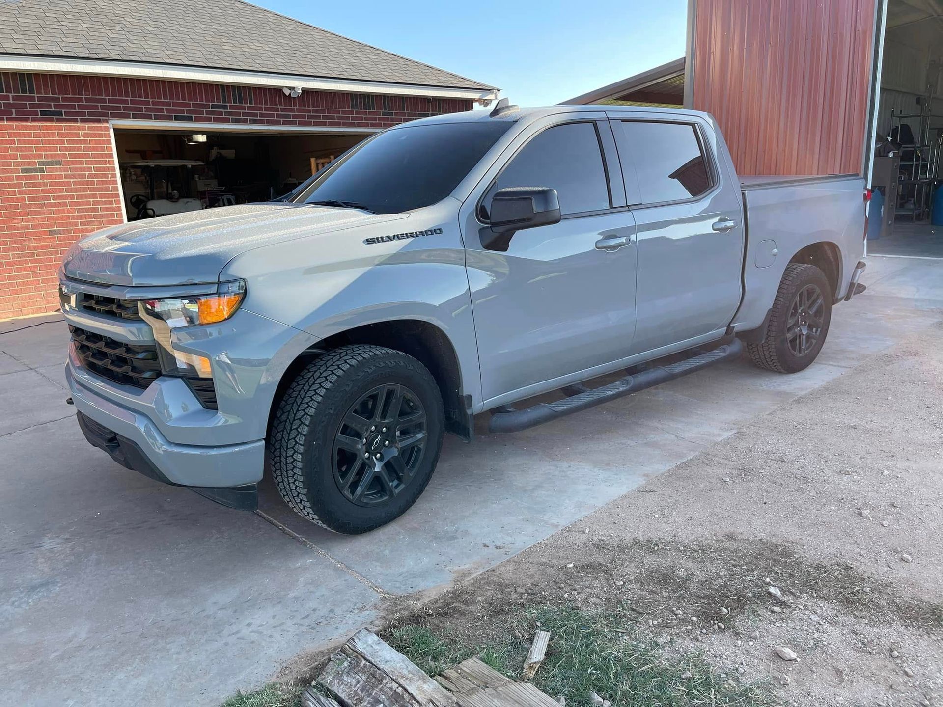 A gray truck is parked in front of a garage.