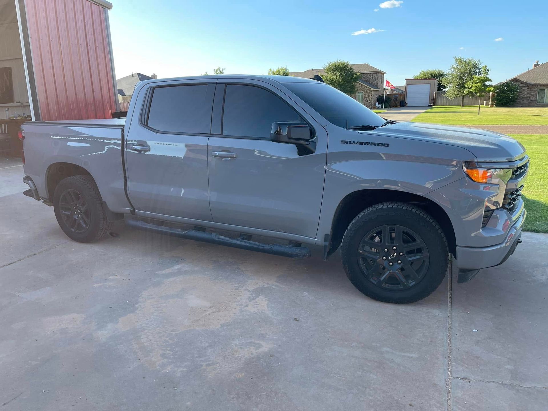 A gray truck is parked in a driveway next to a building.