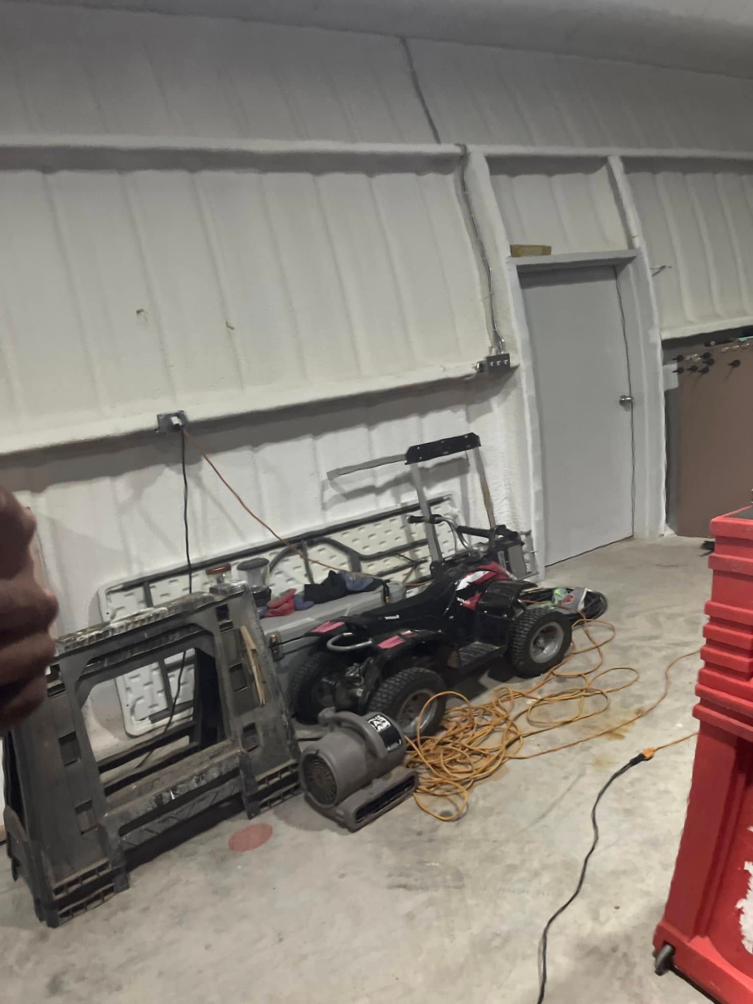 A row of lawn mowers are sitting in a garage.