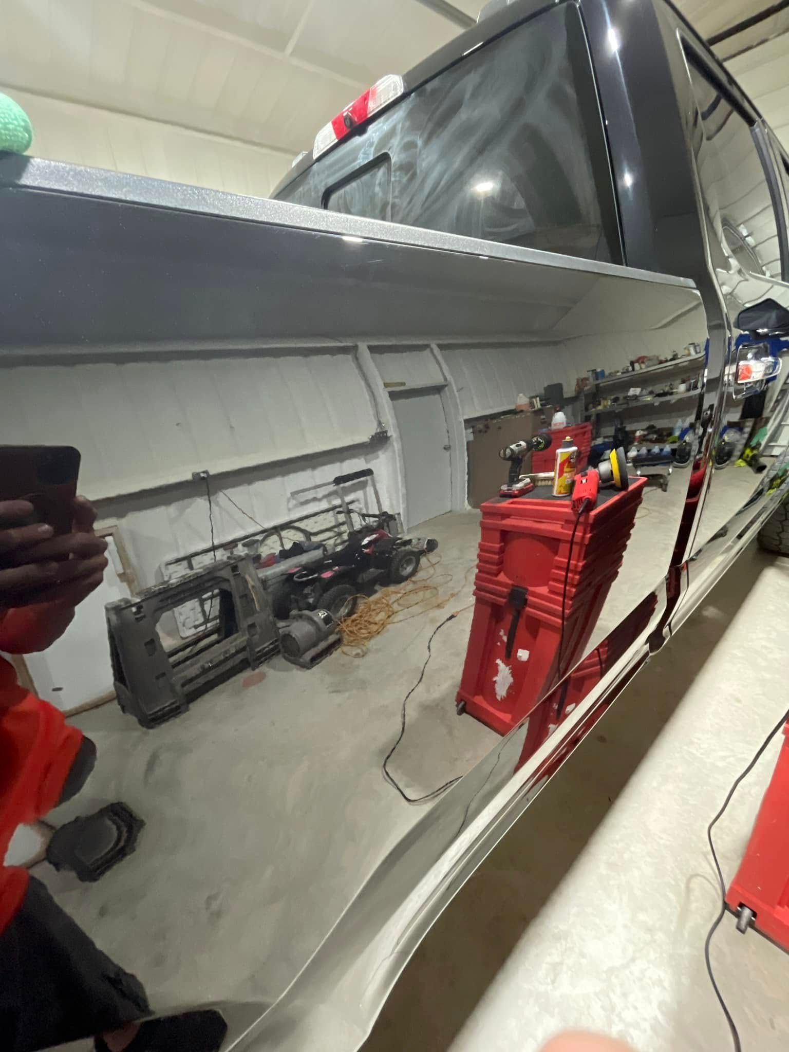 A person is taking a picture of a truck in a garage.