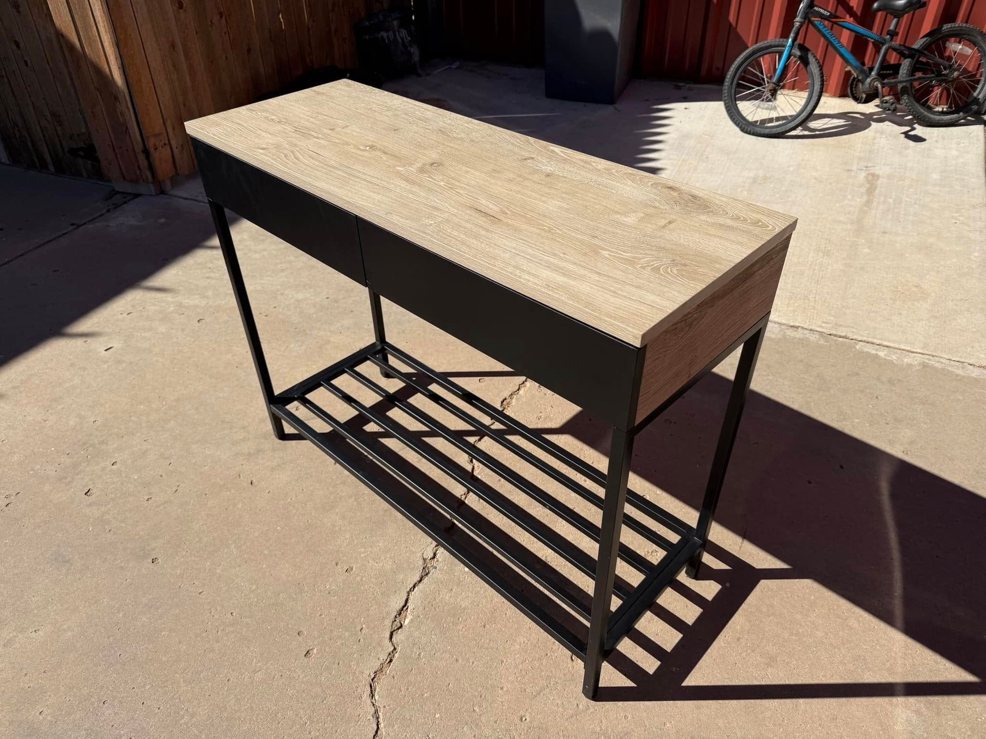 A wooden table with a metal frame is sitting on a concrete surface.