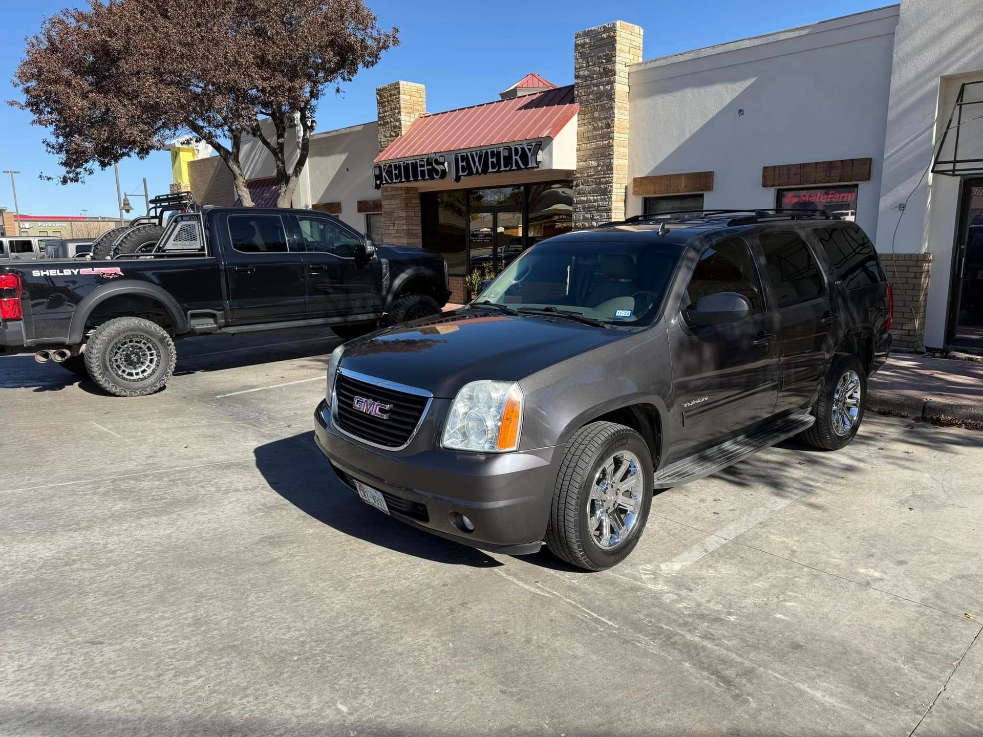 A gmc yukon is parked in a parking lot in front of a building.