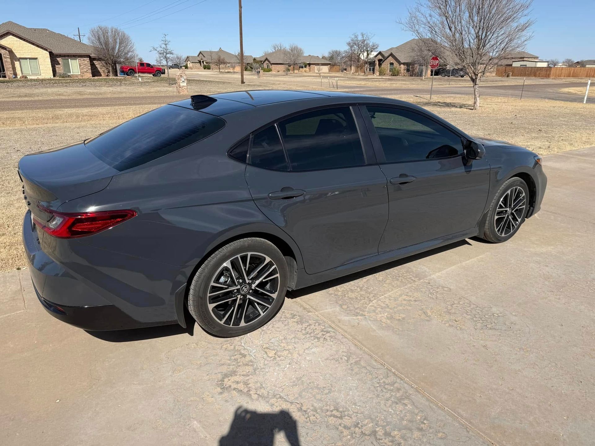 A gray car is parked on the side of the road in a parking lot.