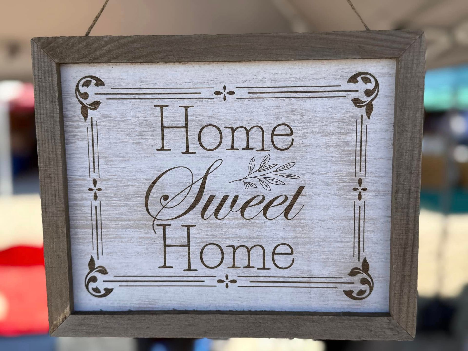 A sign that says home sweet home is hanging on a rope.