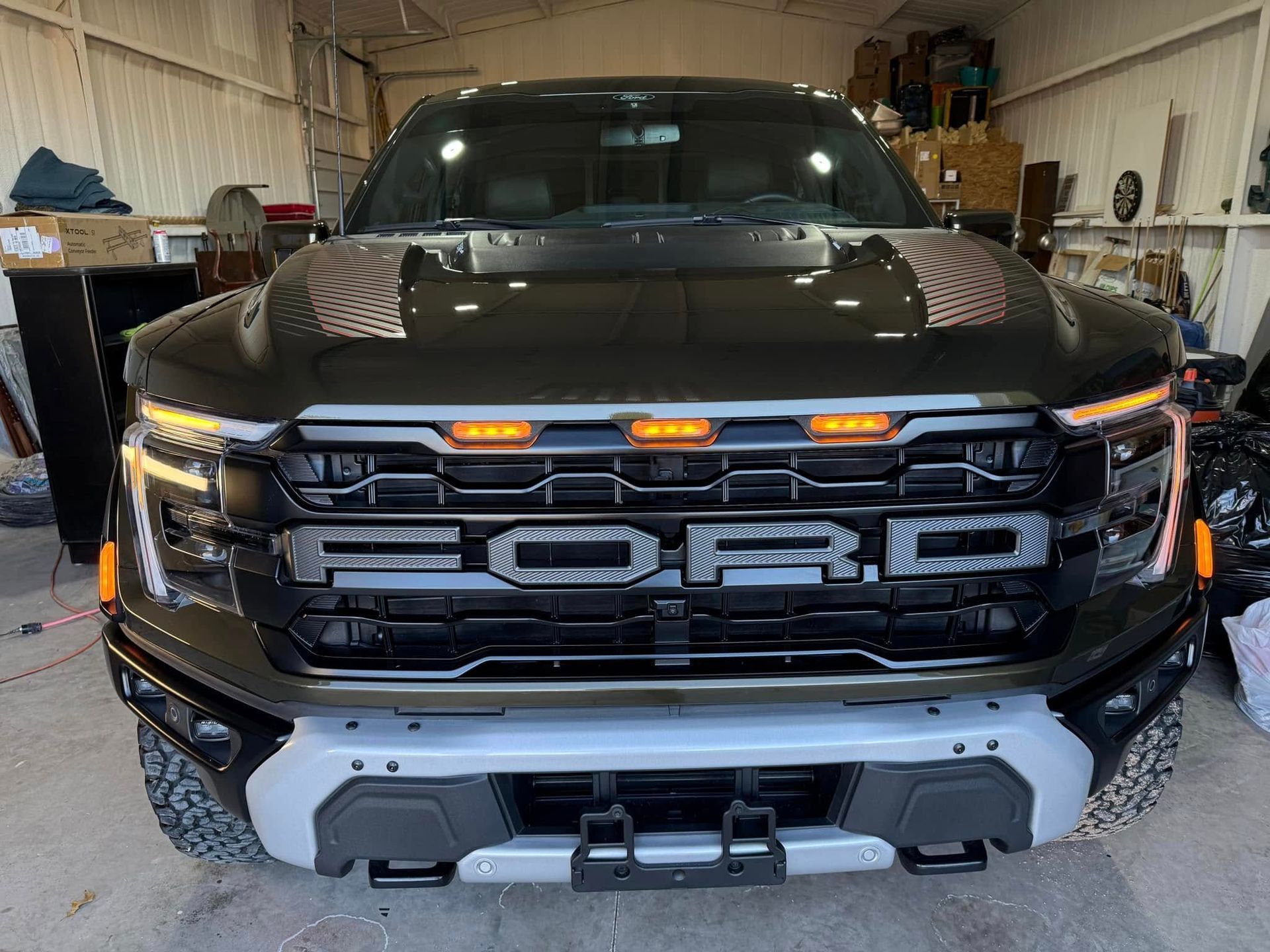 A black ford raptor is parked in a garage.