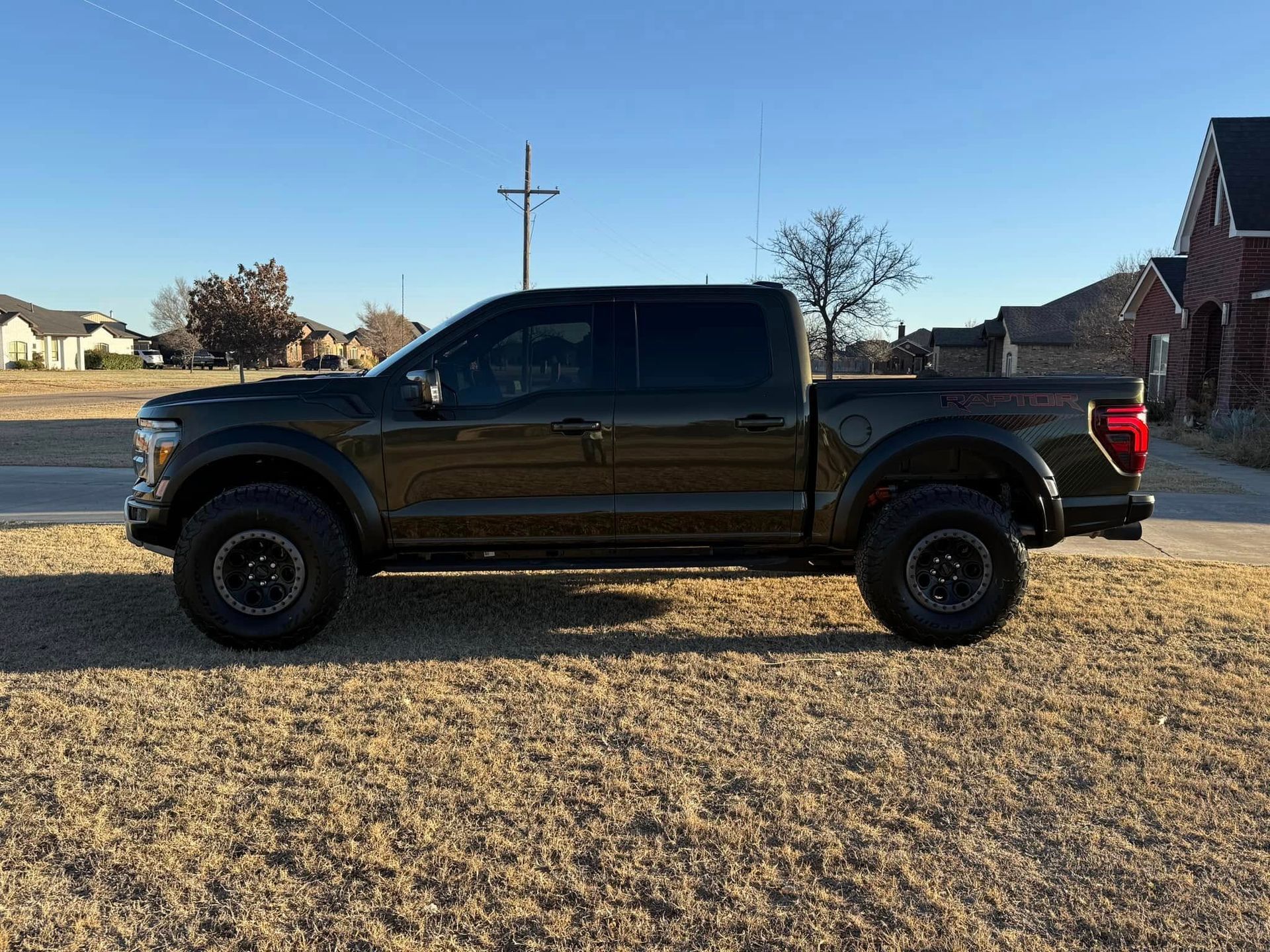 A black pickup truck is parked in a dirt field.