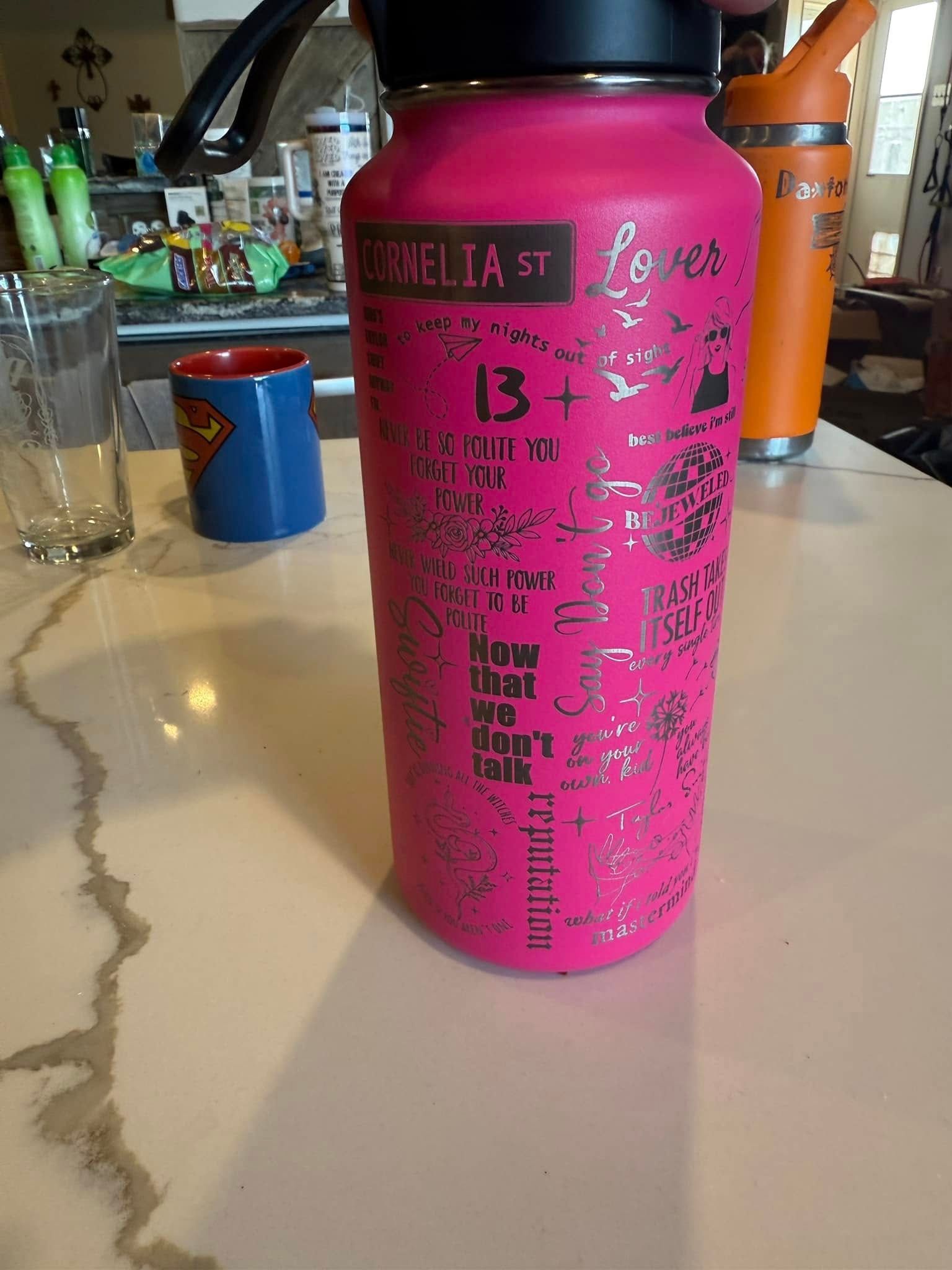 A pink hydro flask water bottle is sitting on a counter.