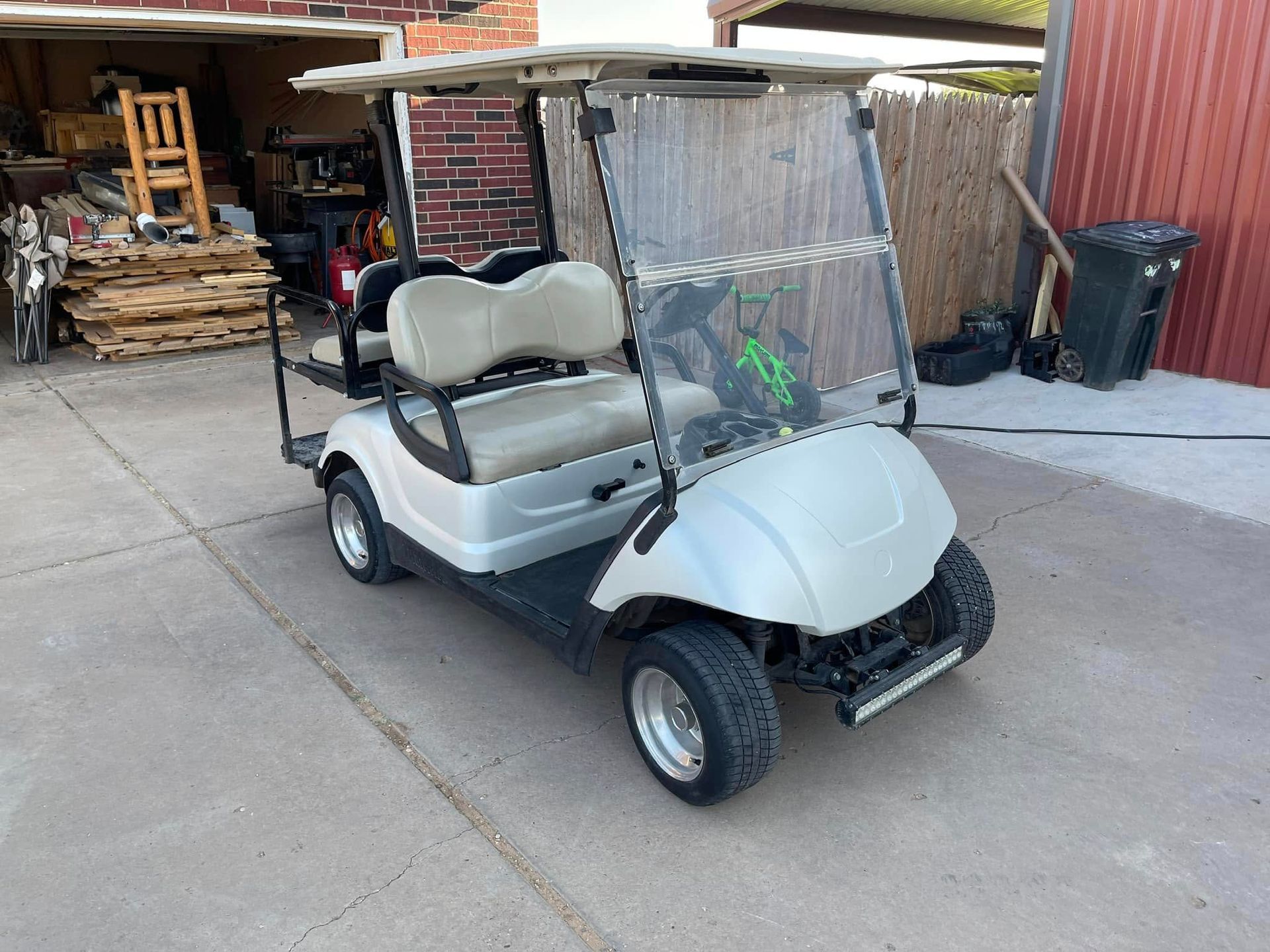 A white golf cart is parked in a driveway in front of a garage.