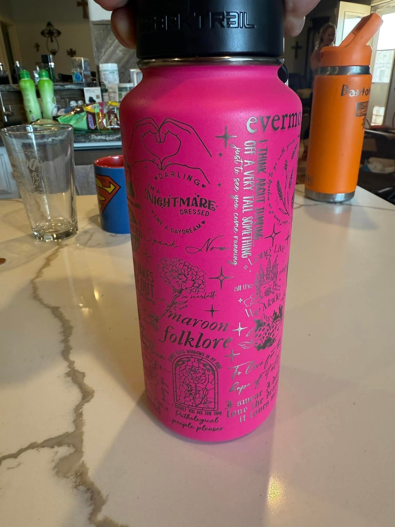 A person is holding a pink hydro flask on a counter.