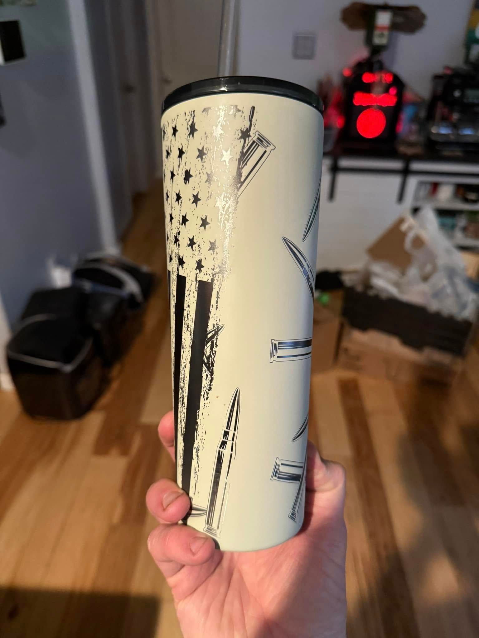 A person is holding a stainless steel tumbler with an american flag on it.
