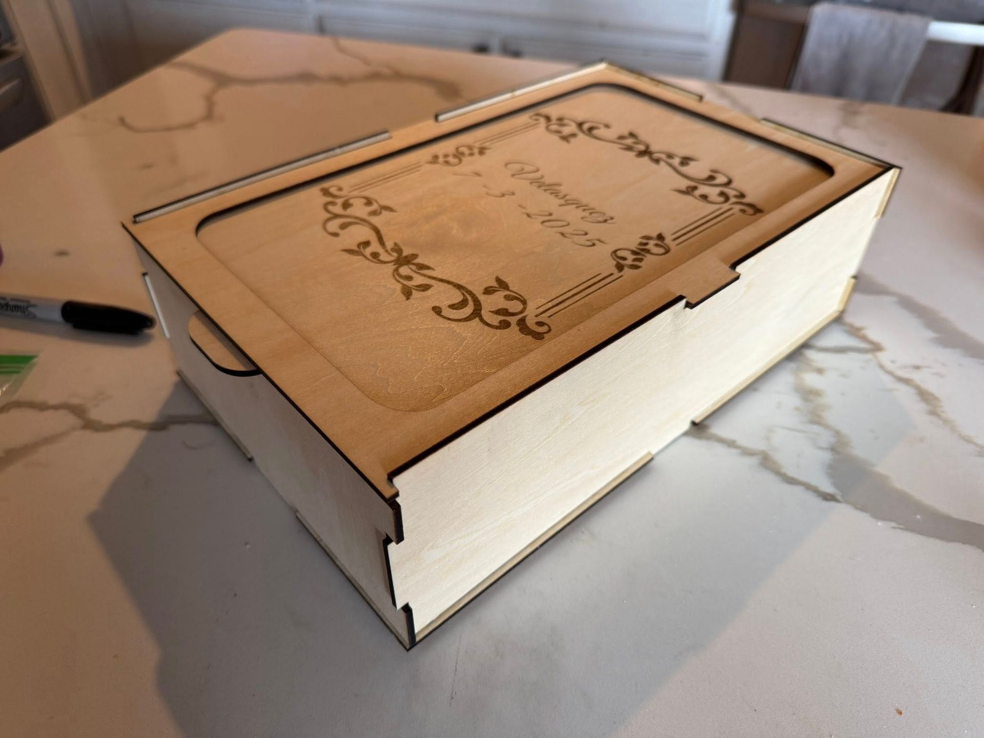 A wooden box is sitting on a marble counter top.