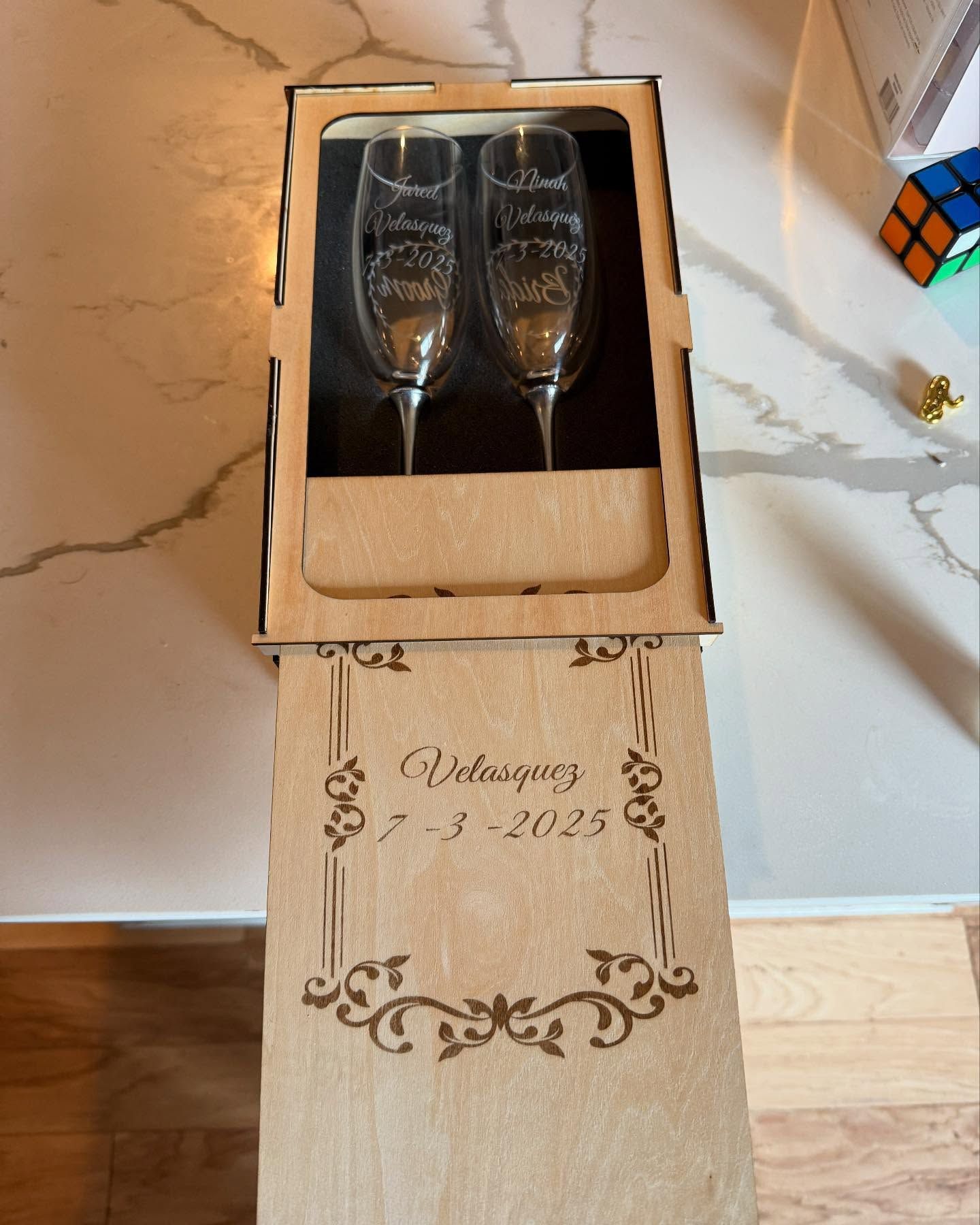 Two champagne flutes are in a wooden box on a table.