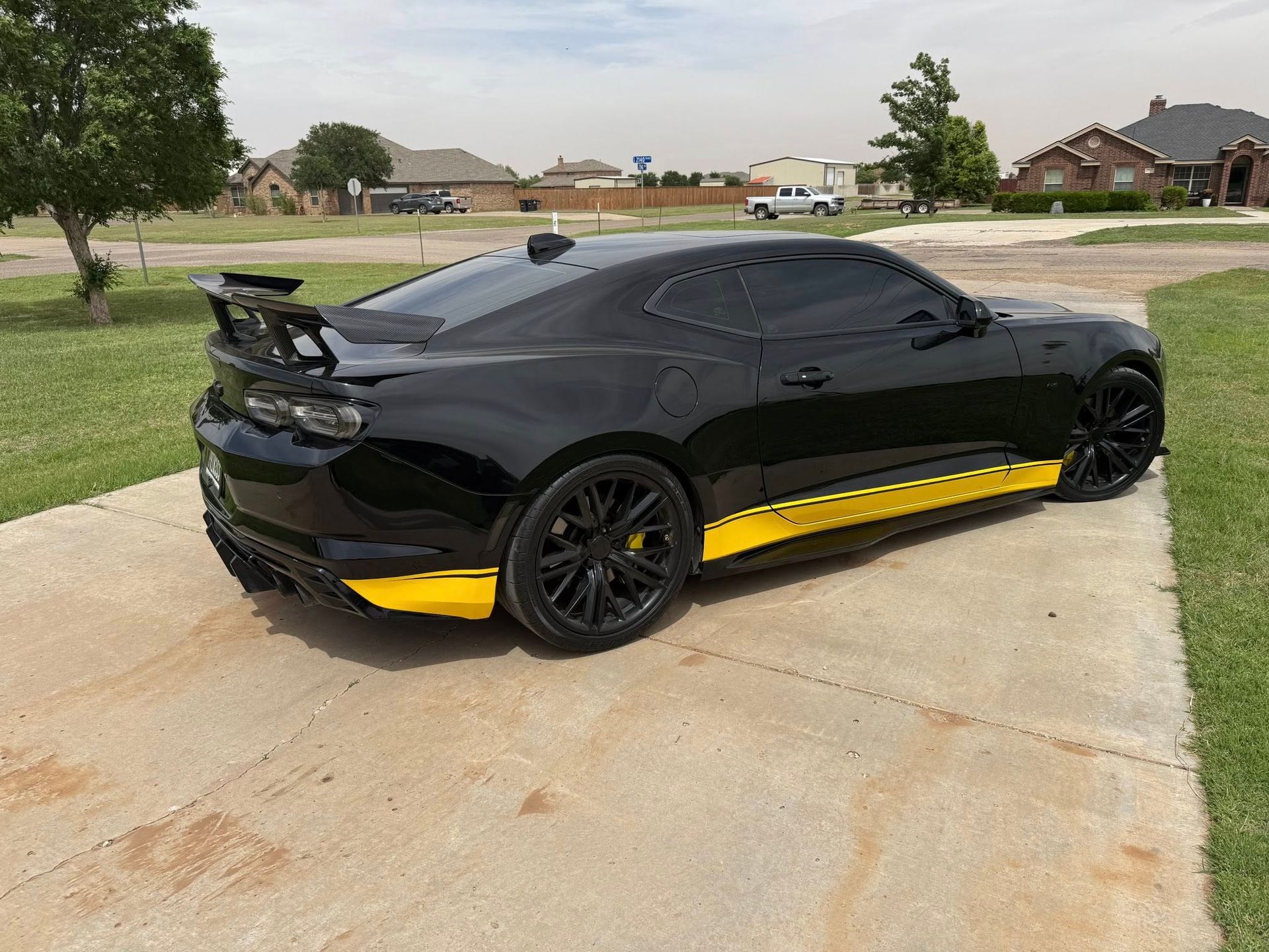 A black car with yellow stripes on the side is parked in a driveway.