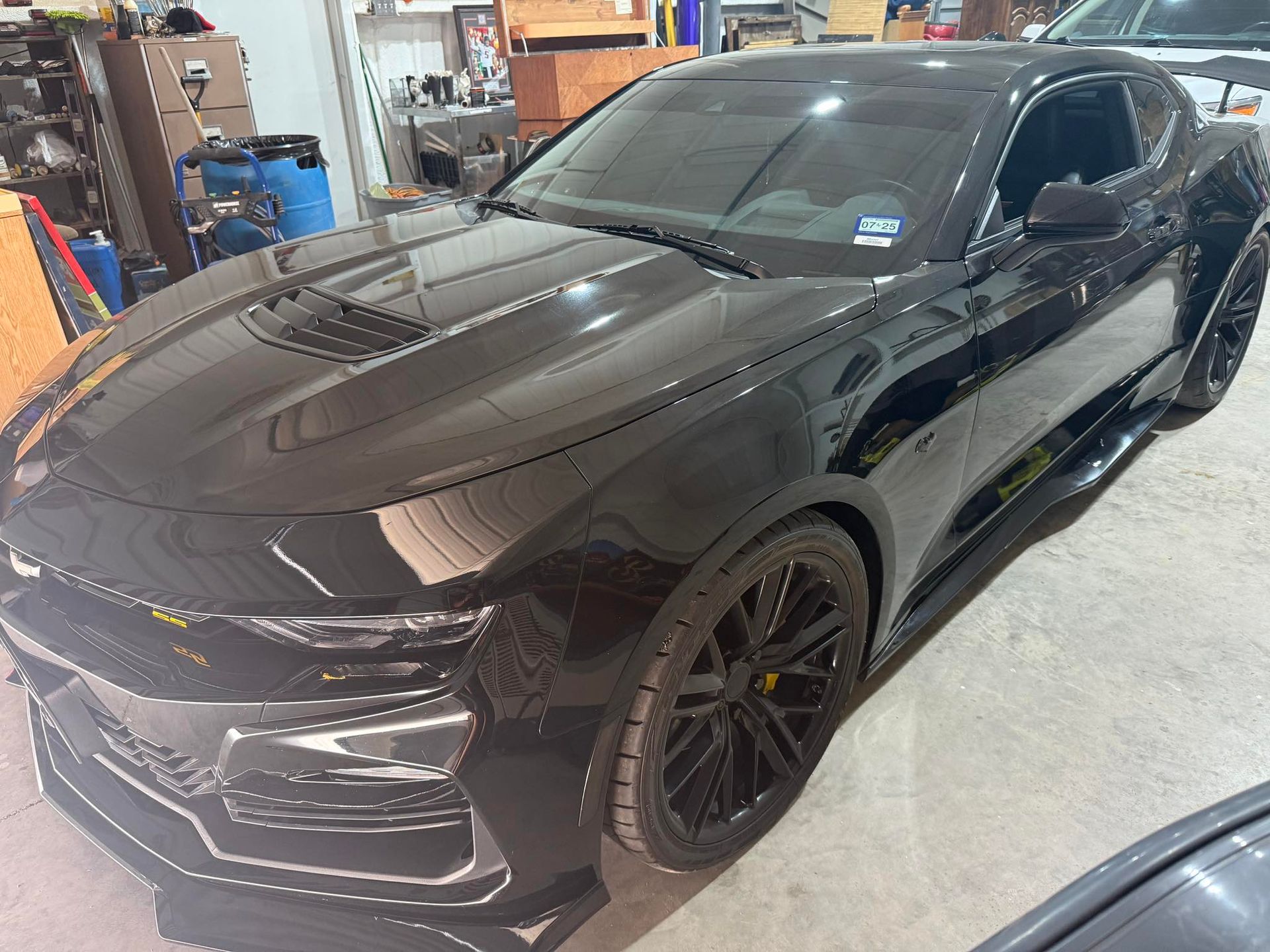 A black sports car is parked in a garage.