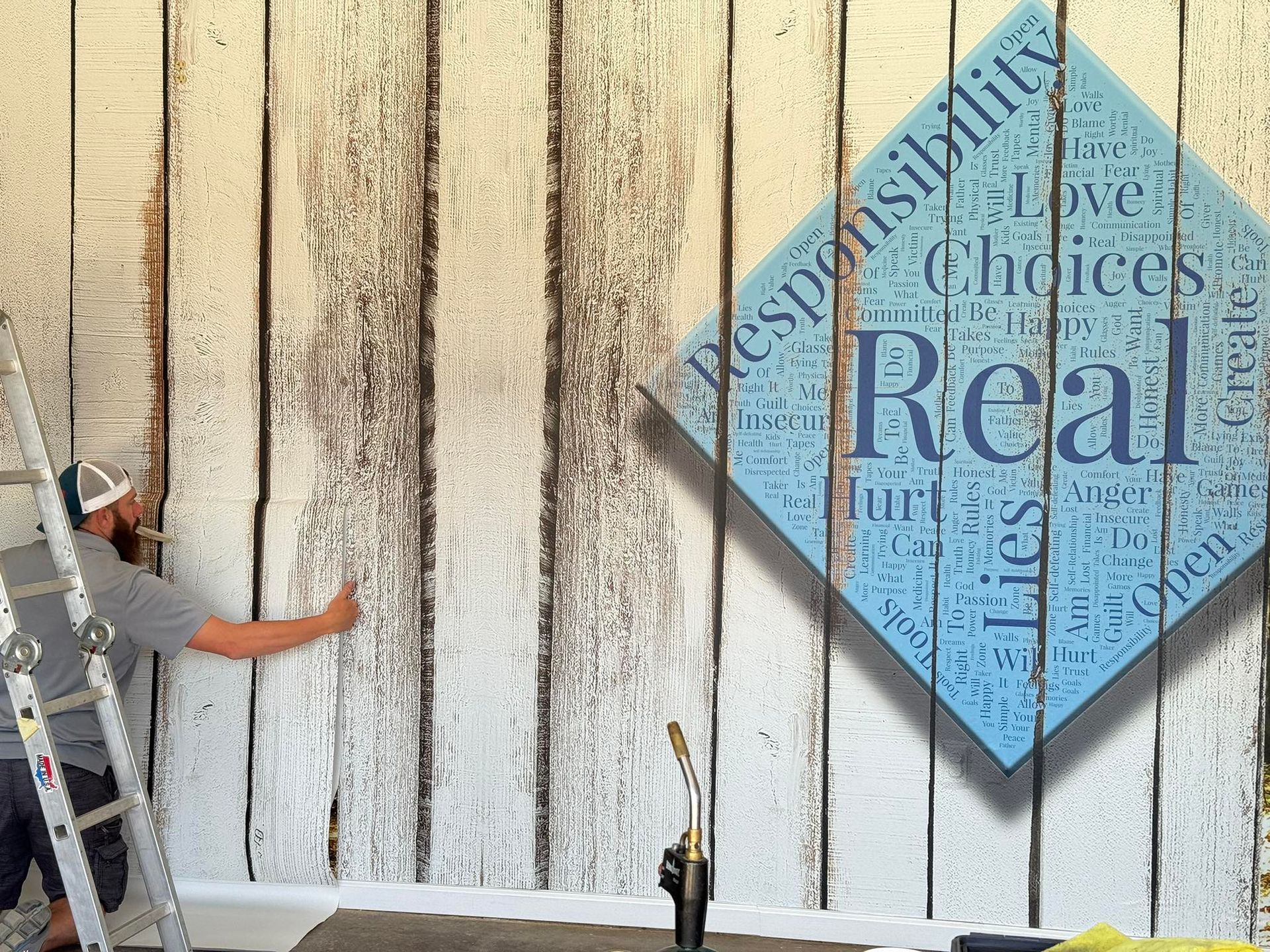 A man is painting a wall with a sign that says real