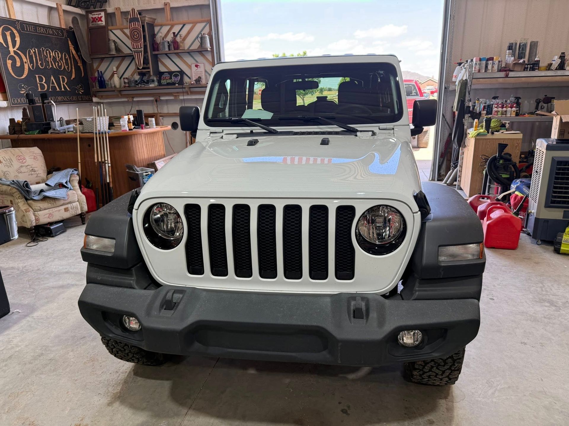 A white jeep is parked in a garage.