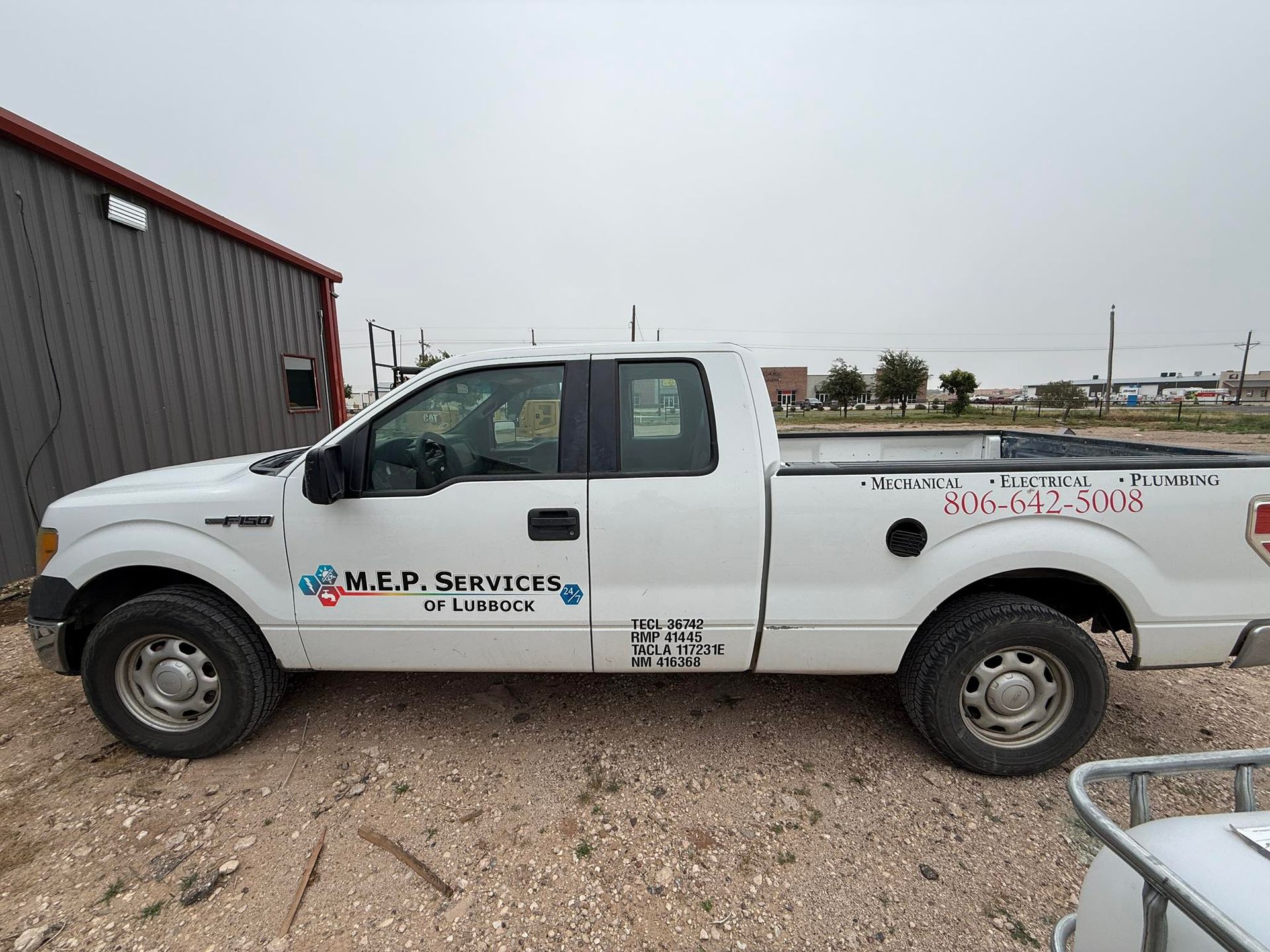 A white pickup truck is parked in a gravel lot.