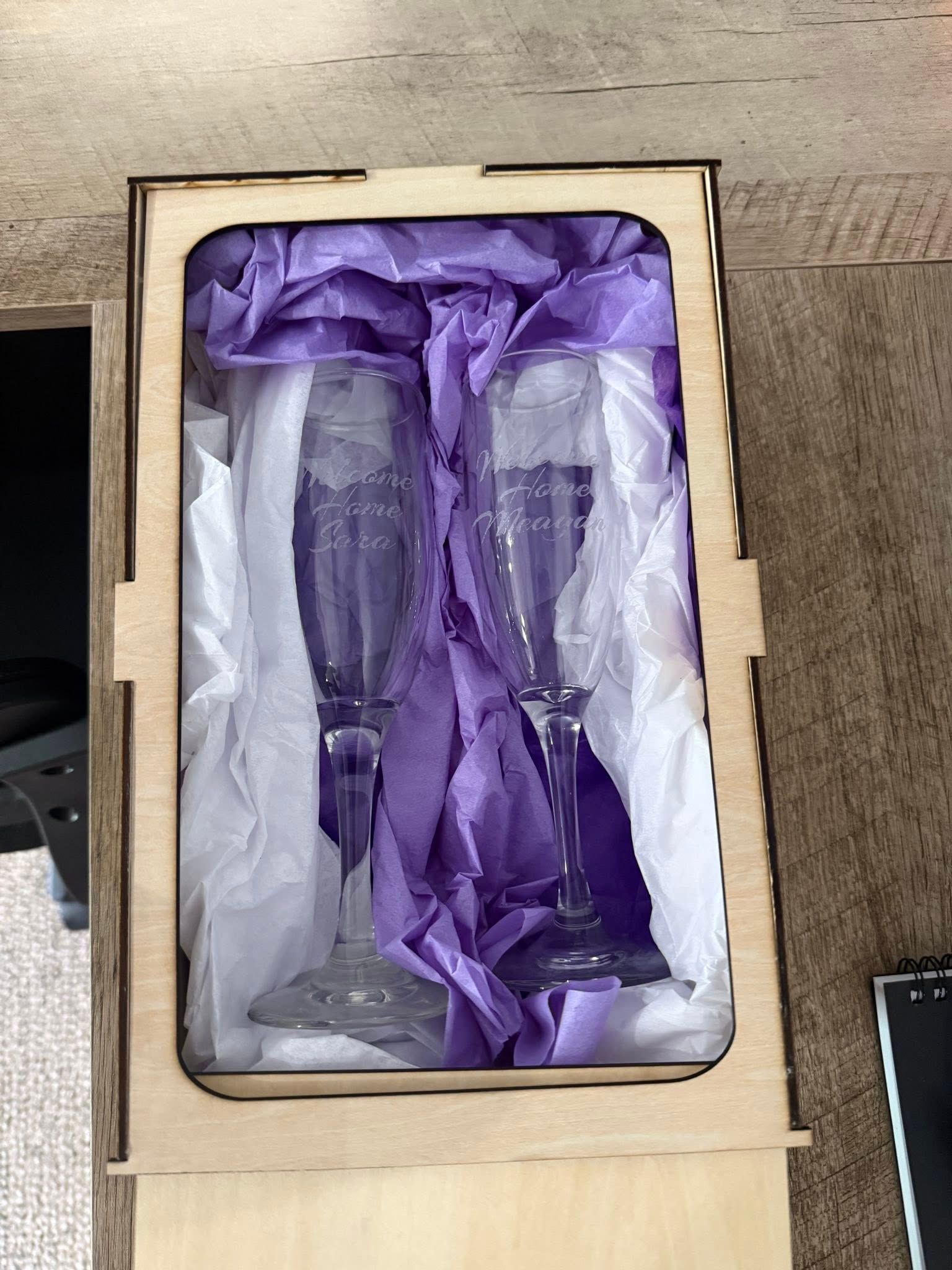 Two champagne flutes are sitting in a wooden box.