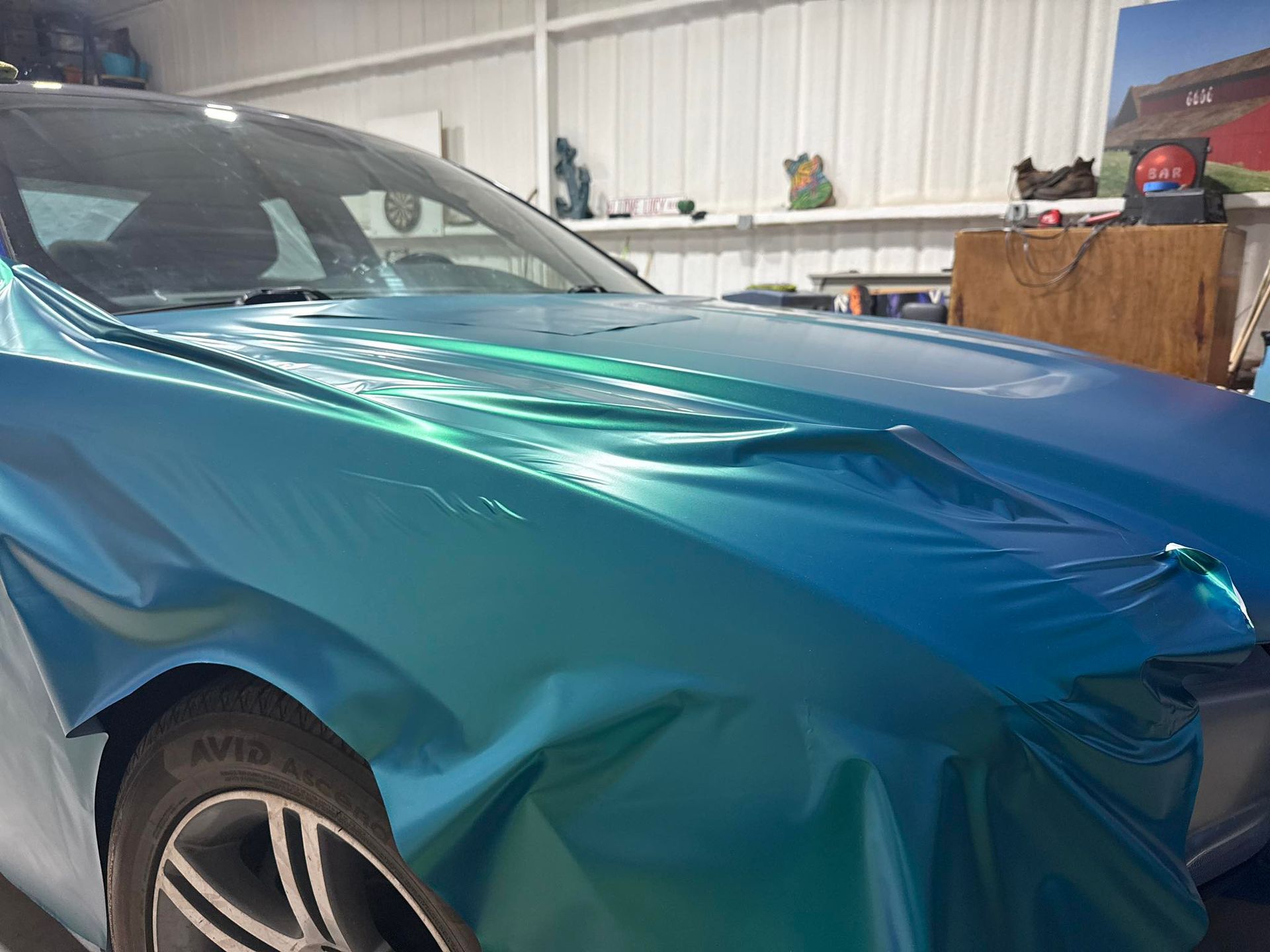 A car is wrapped in a blue metallic wrap in a garage.