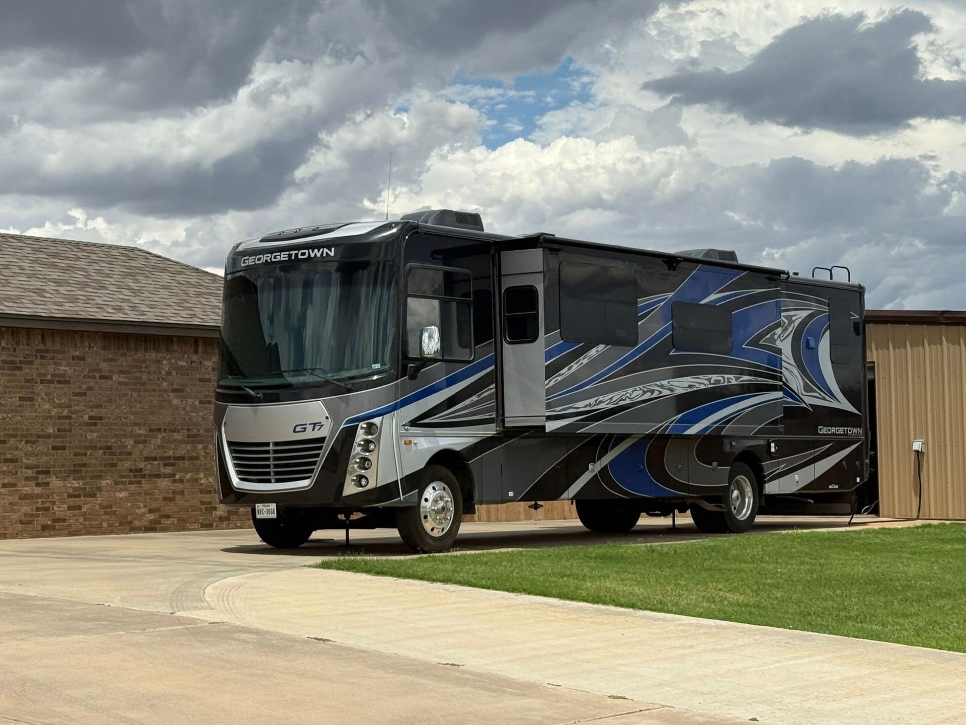 A large rv is parked in a driveway in front of a house.