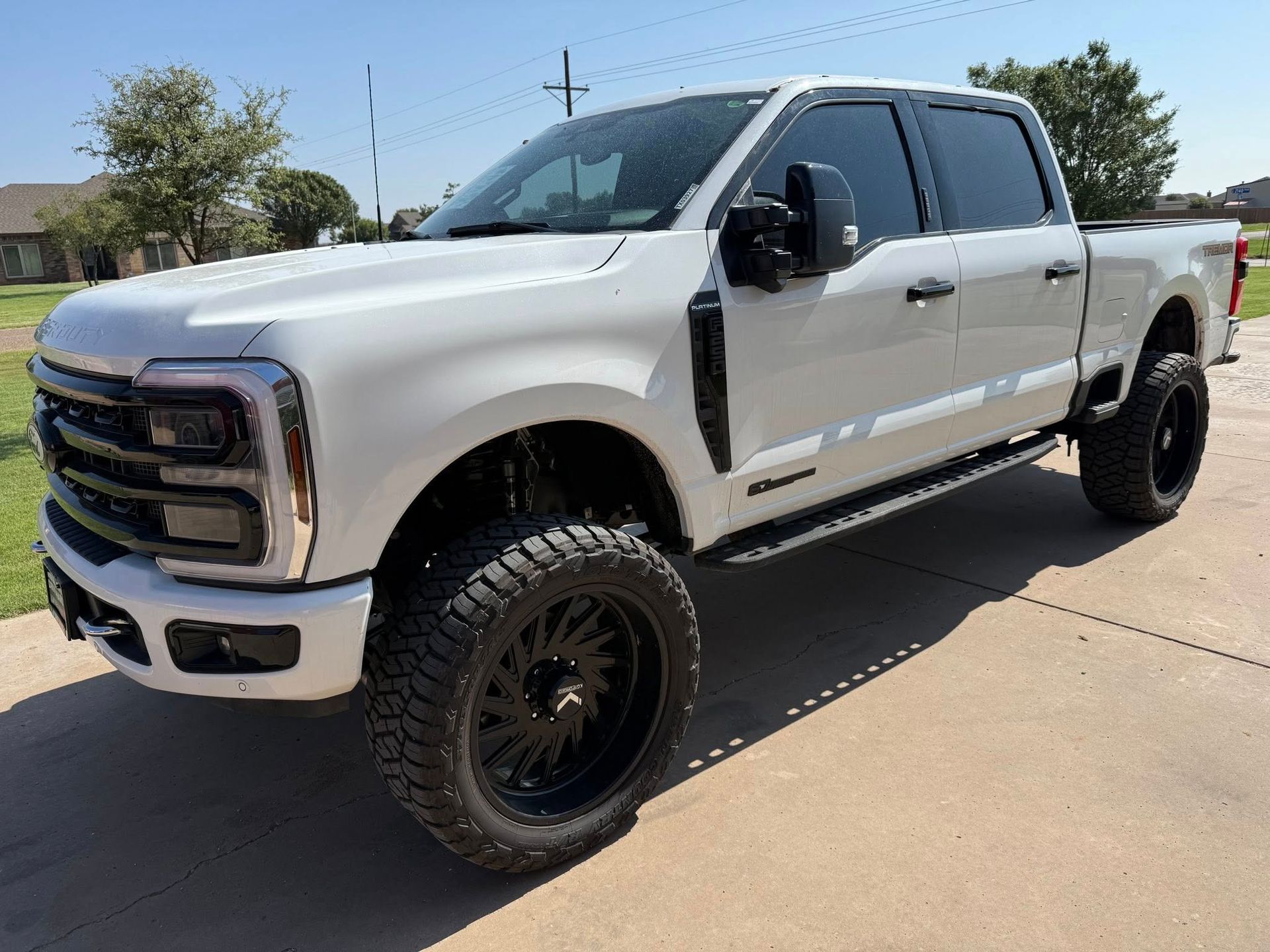 A white pickup truck is parked on a concrete driveway.