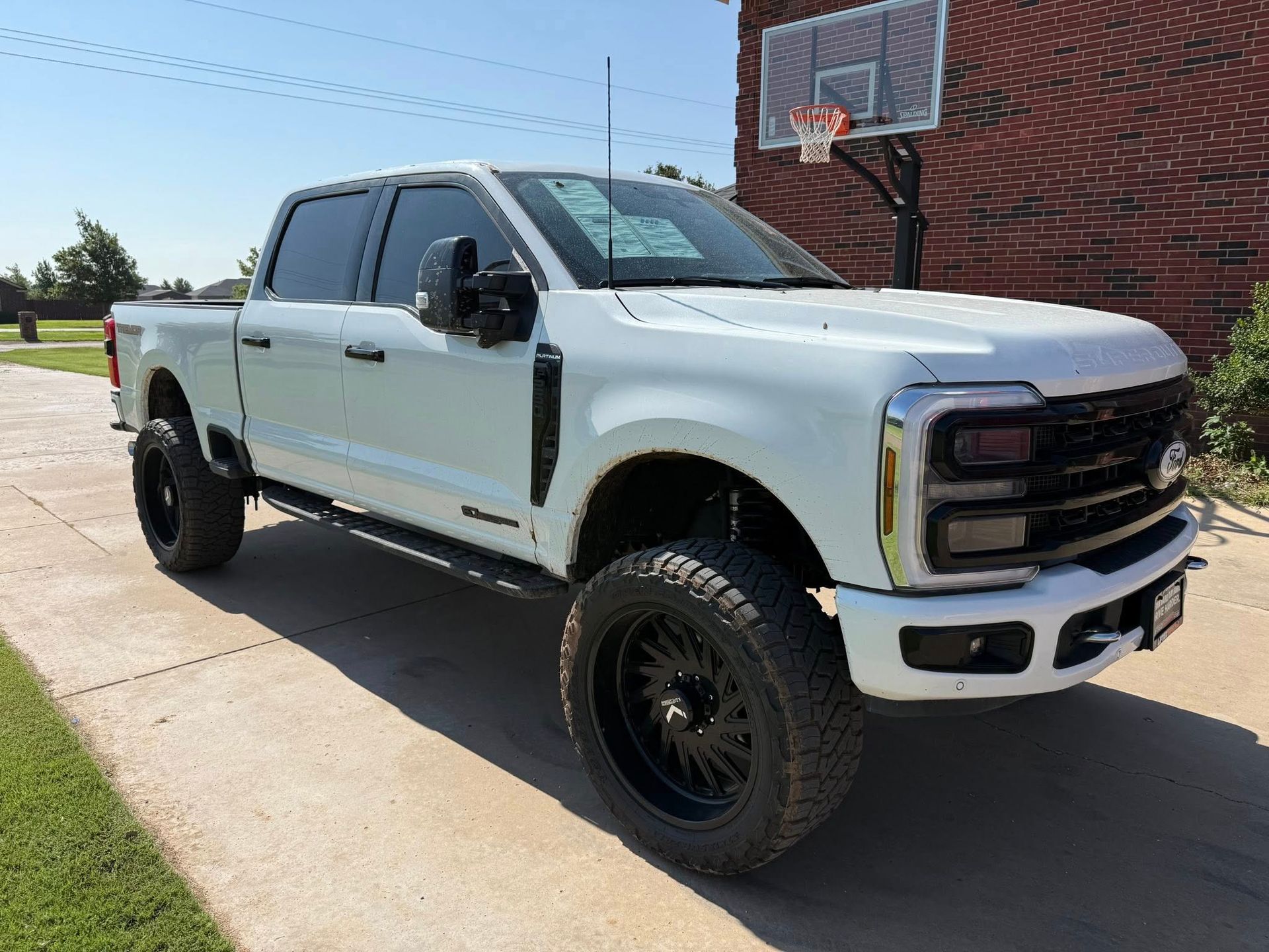 A white truck is parked on the side of the road next to a basketball hoop.