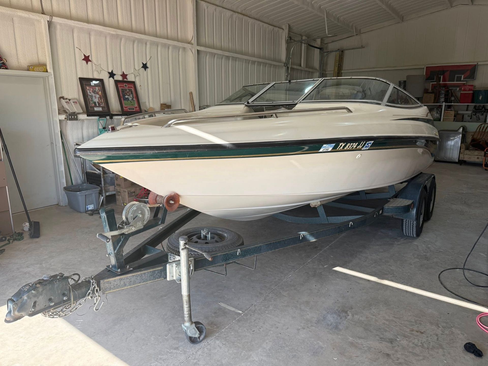 A white boat is parked on a trailer in a garage.
