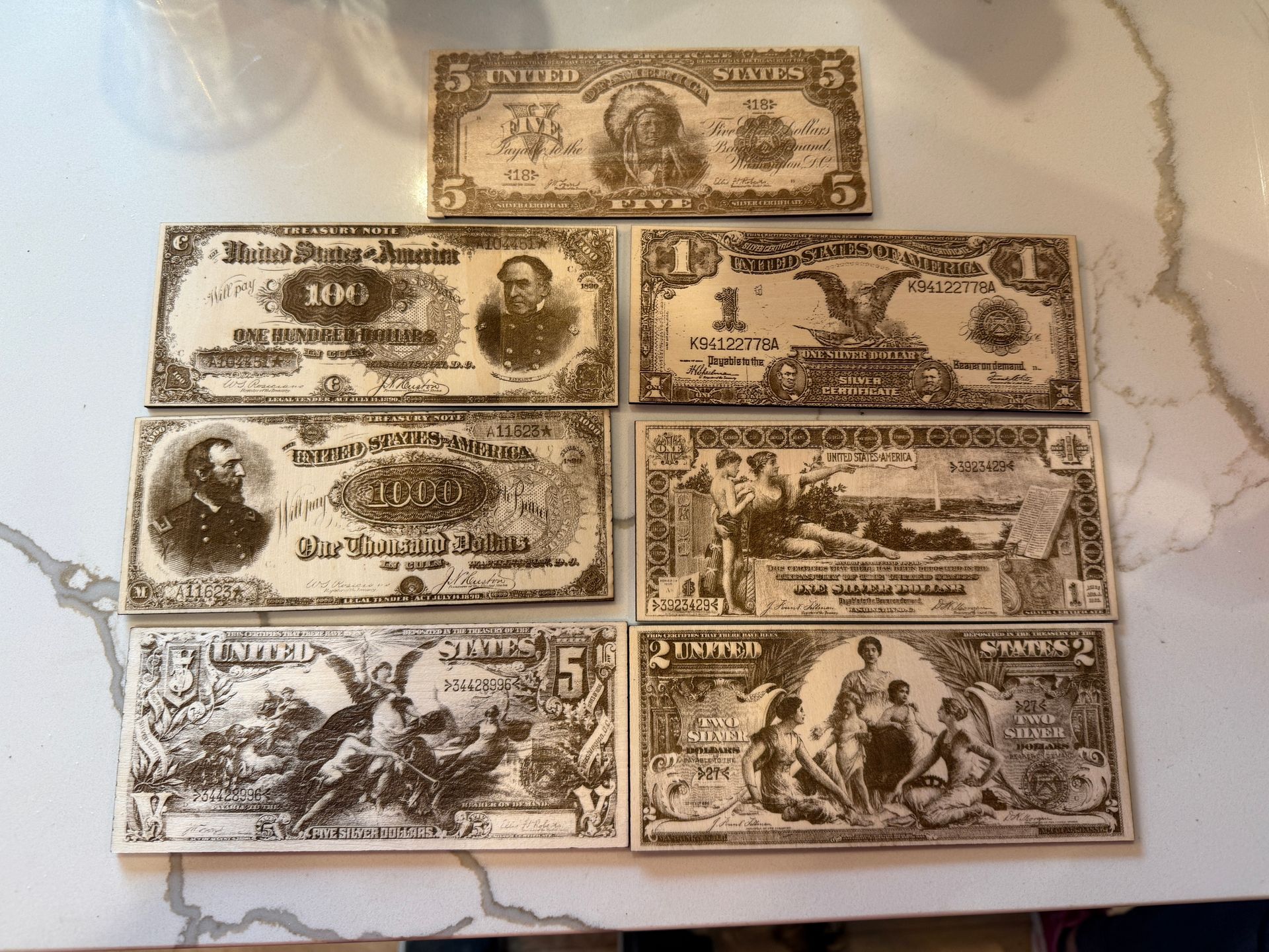Arrangement of antique US paper currency on a white surface.  Denominations include $1, $5, and $100 bills, featuring portraits and intricate designs.