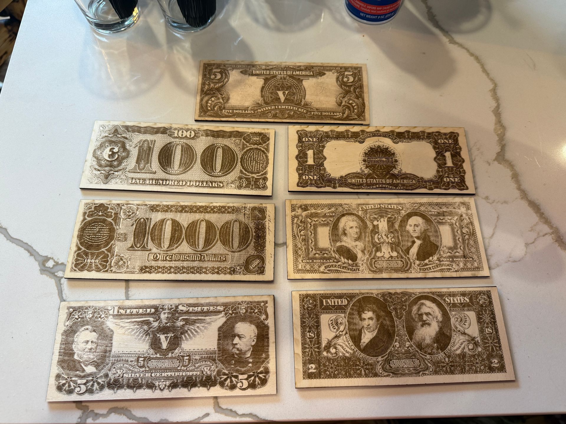 Collection of old US bills, including a $1000, $100, and $1, arranged on a white marble countertop.