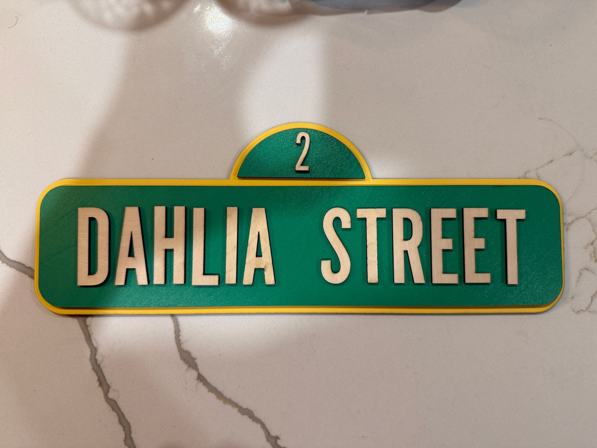 Green street sign with gold lettering that reads 