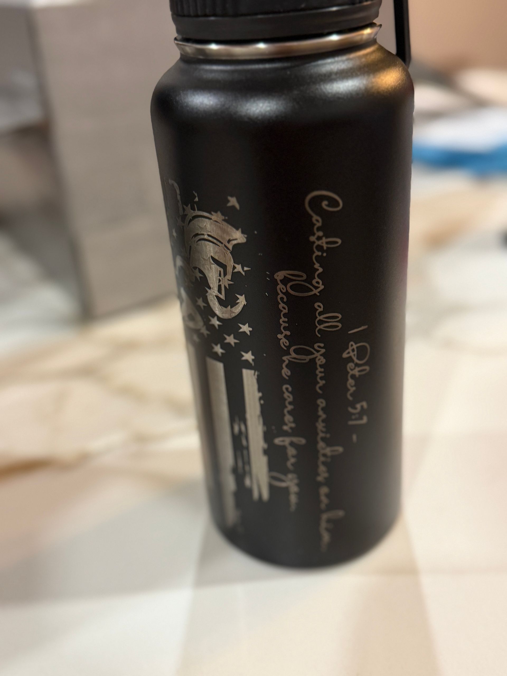 Black water bottle with etched design. Features a horse and flag motif with 