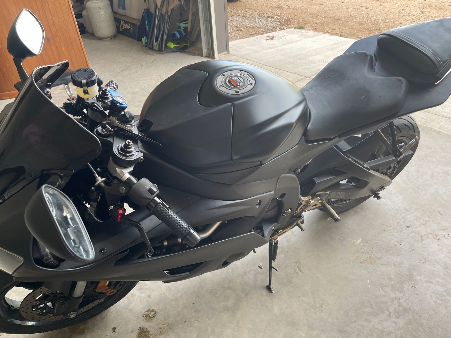 Black sport motorcycle parked in a garage. It has a black matte finish with a black seat and fairings.