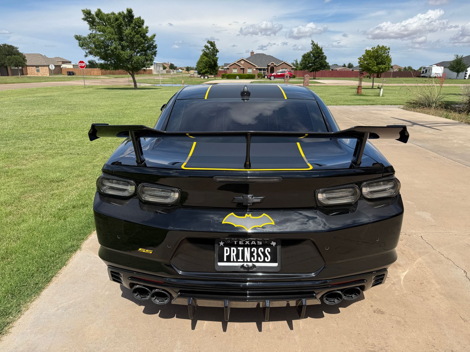 Black Chevrolet Camaro customized with a Batman theme, including a rear spoiler, yellow accents, and a Batman emblem license plate.