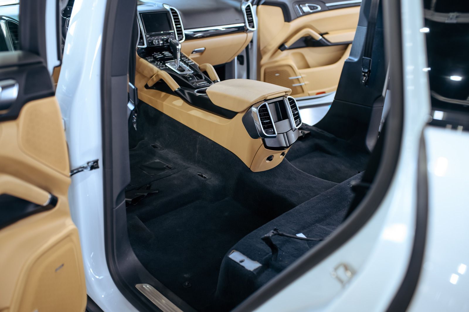 Interior of a white car with tan and black accents, carpet partially removed.