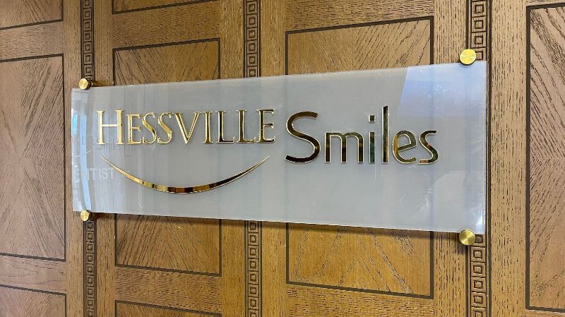 A sign for hessville smiles hangs on a wooden wall