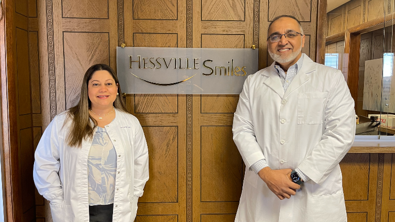 A man and a woman are standing next to each other in front of a sign.