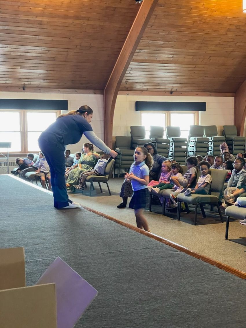 A woman is standing in front of a group of children in a church.