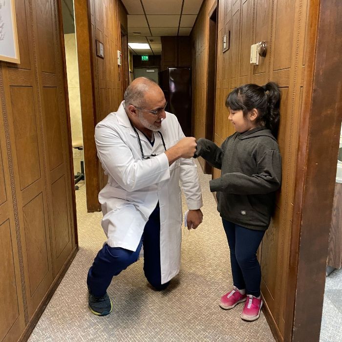 A doctor is talking to a little girl in a hallway.